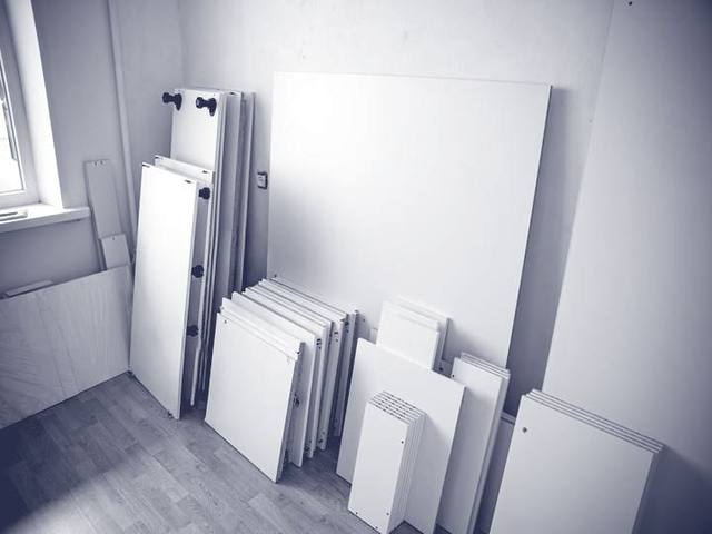 Nach Größe sortierte Schrankplatten lehnen an der Wand eines leeren Zimmers